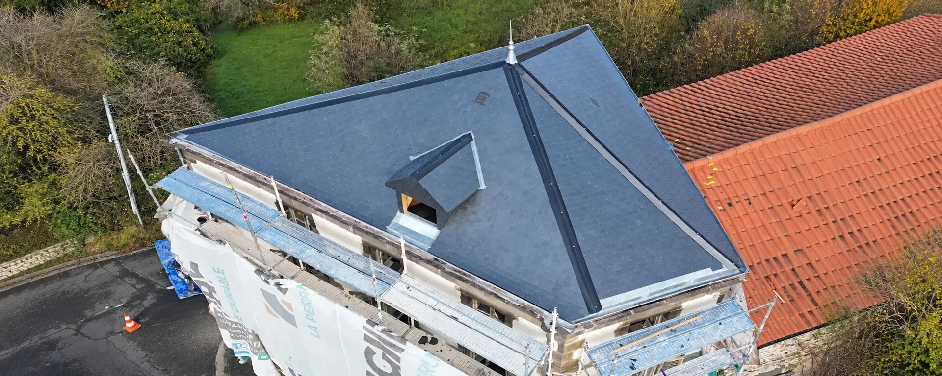 Toiture en ardoise avec lucarne, sous un ciel nuageux, dans le Puy-de-Dôme