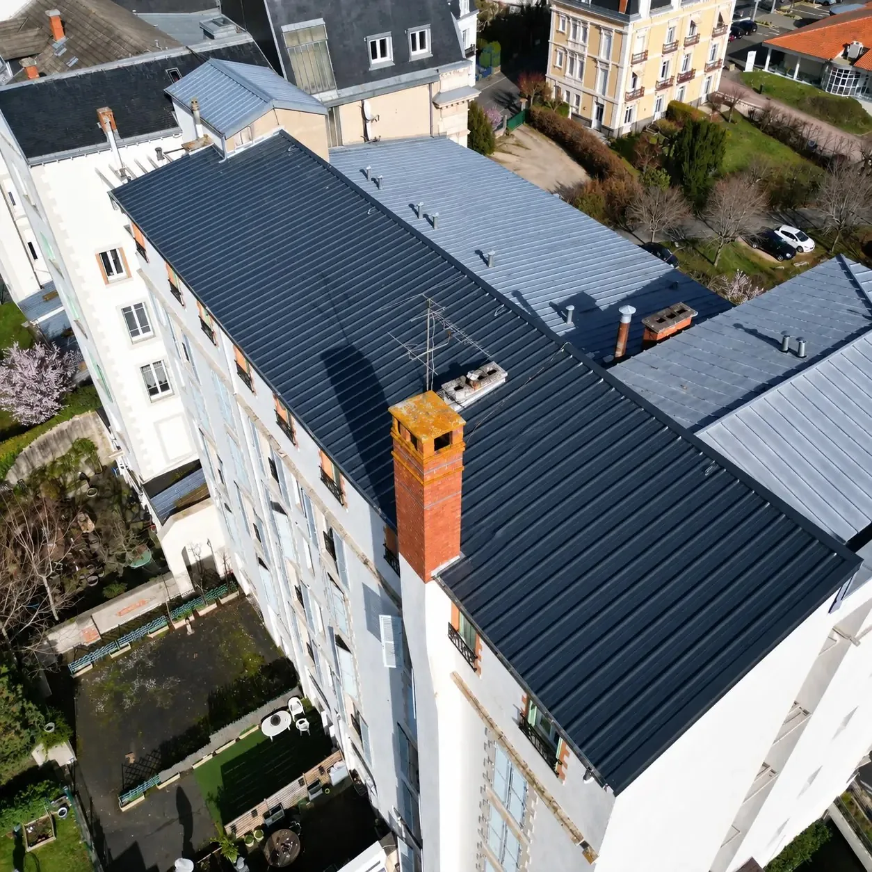 Vue de drone d’un immeuble dont la toiture en bac acier gris est rénovée par MD Bâtiment
